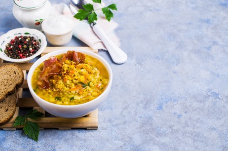 Thick pea soup with bacon and vegetables in a plate on the table. Selective focus.の写真素材