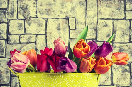 Bouquet of multicolored tulips in a vase on the table by the wall. Selective focus.の写真素材