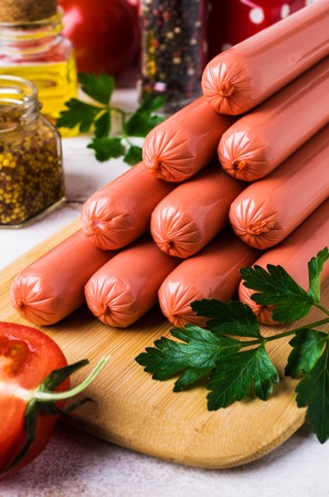 Raw sausages in peel with tomatoes and spices on wooden background. Selective focus.の写真素材