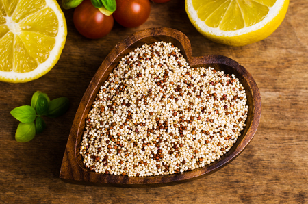 Dry mixture of quinoa grains on wooden background with tomatoes and lemon. Selective focus.の写真素材