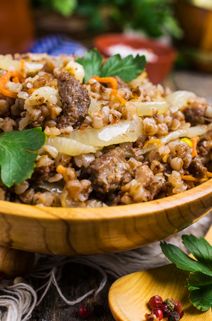 Traditional buckwheat porridge with meat and vegetables in bowl on wooden background. Selective focus.の写真素材