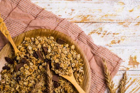 Dry oat flakes with raisins and chocolate in a dish on the table. Selective focus.の写真素材