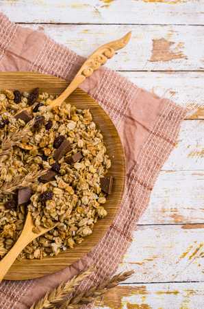 Dry oat flakes with raisins and chocolate in a dish on the table. Selective focus.の写真素材