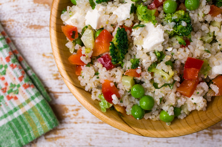 Salad of crushed cereals with vegetables and cheese in a dish on a wooden background. Selective focus.の写真素材