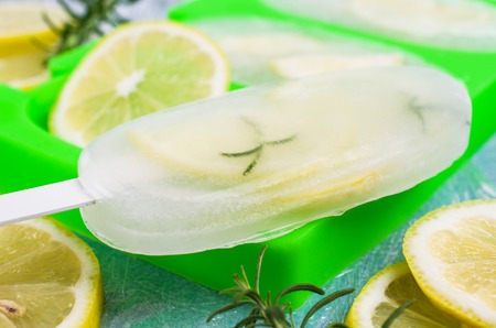 Frozen fruit ice with lemon and rosemary on a stick. Selective focus.の写真素材