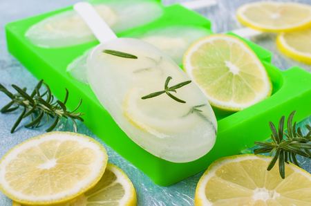 Frozen fruit ice with lemon and rosemary on a stick. Selective focus.の写真素材