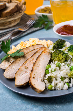 Slices of fried meat with rice, vegetables and omelet in a dish on the table. Selective focus.の写真素材