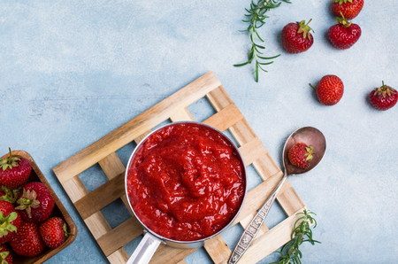 Red strawberry jam in a metal ladle on the table. Selective focus.の写真素材