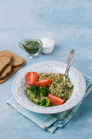 Vegetables with quinoa and green sauce in a dish on the table. Selective focus.の写真素材