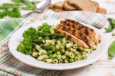 Pasta in green sauce with vegetables and meat. Selective focus.の写真素材