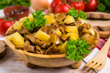 Fried mushrooms with potatoes and onions in a dish on the table. Selective focus.の写真素材