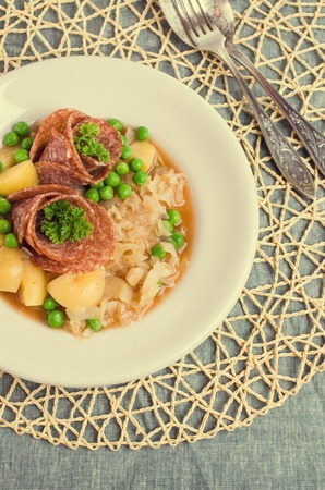 Salami with stewed vegetables in a dish on the table. Selective focus.の写真素材