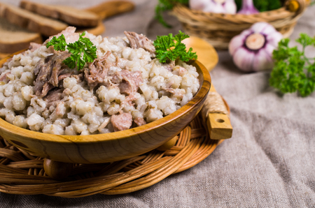 Traditional pearl barley porridge with meat in a dish on the table. Selective focus.の写真素材