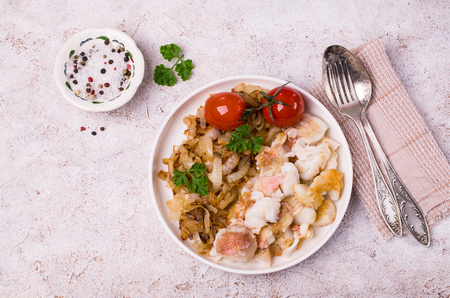 Slices of fried fish with vegetables and parsley in a dish on the table. Selective focus.の写真素材