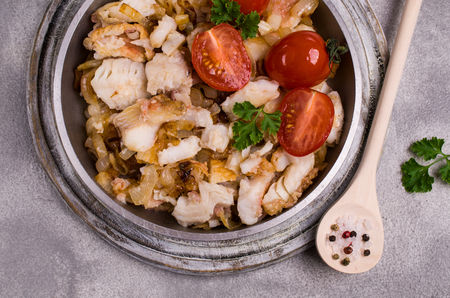 Slices of fried fish with vegetables and parsley in a dish on the table. Selective focus.の写真素材