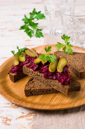 Sandwiches with beet and pickled cucumber on dark bread on a wooden background. Selective focus.の写真素材