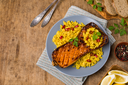 Baked Butternut squash with spicy rice on wooden background. Selective focus.の写真素材