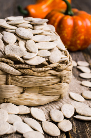 Pumpkin seeds in basket on wooden background. Selective focus.の写真素材