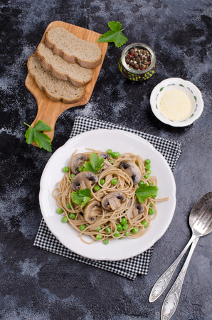 Dark pasta with mushrooms and peas on a slate background. Selective focus.の写真素材