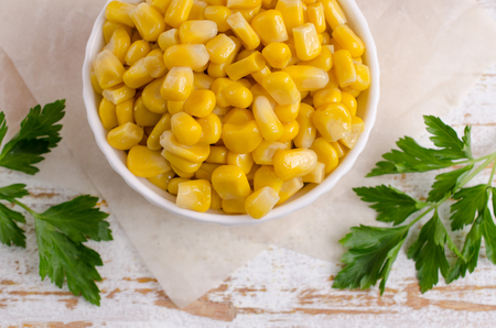 Sweet canned corn in a dish on a wooden background. Selective focus.の写真素材
