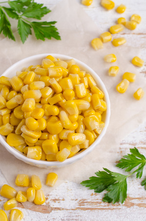 Sweet canned corn in a dish on a wooden background. Selective focus.の写真素材