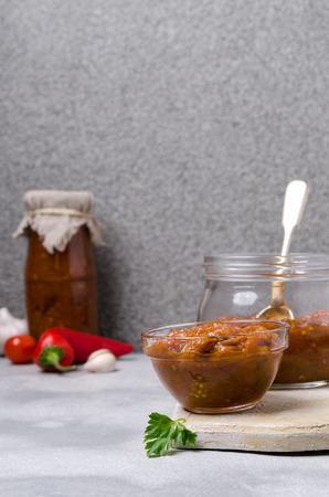 Traditional spicy vegetable sauce in a glass jar on the table. Selective focus.の写真素材