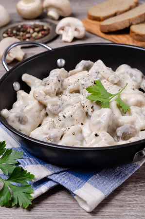Slices of mushrooms and meat with white sauce on wooden background. Selective focus.の写真素材