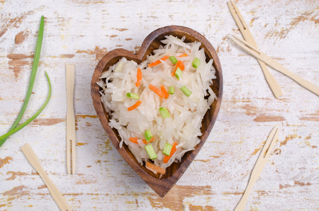 Traditional sauerkraut with carrots and onions on wooden background. Selective focus.の写真素材