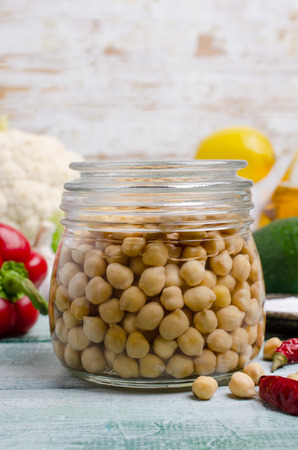 Canned chickpeas in a glass jar on a wooden background. Selective focus.の写真素材
