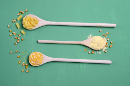 Dry corn products. Grains, polenta, flour, pasta. Green wooden background. Selective focus.