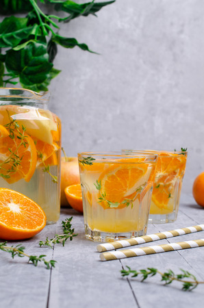 Infused water with fruit and thyme in glass on wooden background. Selective focus.の写真素材