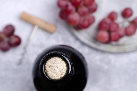 Cork in a bottle of wine on the background of large grapes on slate. Selective focus.