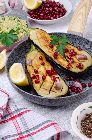 Fried eggplant with couscous and pomegranate seeds in a bowl on a slate background. Selective focus.の写真素材