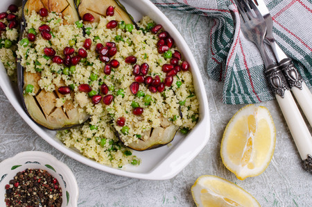 Fried eggplant with couscous and pomegranate seeds in a bowl on a slate background. Selective focus.の写真素材