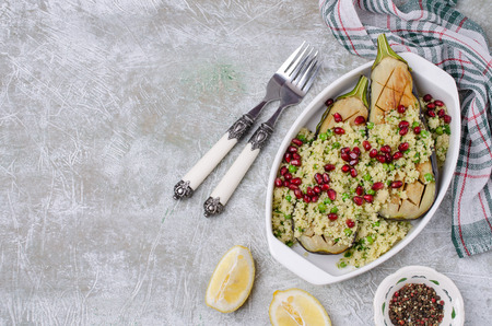 Fried eggplant with couscous and pomegranate seeds in a bowl on a slate background. Selective focus.の写真素材