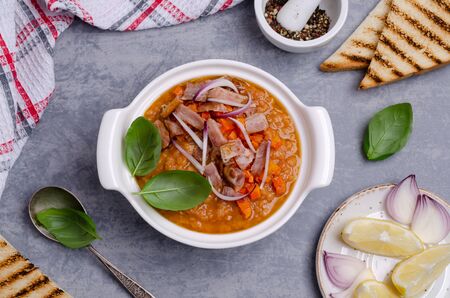 Thick soup with lentils, slices of meat and vegetables in a dish on a wooden background. Selective focus.の写真素材