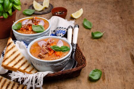 Thick soup with lentils, slices of meat and vegetables in a dish on a wooden background. Selective focus.の写真素材