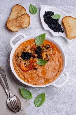 Red lentils with fried seafood and black caviar in a dish on a slate background. Selective focus.の写真素材