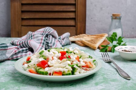 Fresh vegetable salad with cottage cheese in ceramic dish on wooden background. Selective focus.の写真素材