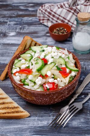 Fresh vegetable salad with cottage cheese in ceramic dish on wooden background. Selective focus.の写真素材