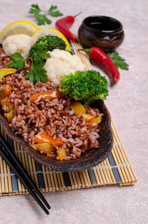 Unpolished red rice with vegetables in a ceramic dish on a slate background. Selective focus.の写真素材