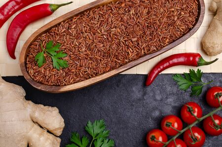Red unpolished rice in a wooden bowl on a slate background. Selective focus.の写真素材