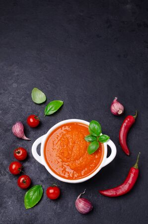 Homemade vegetable red sauce in ceramic bowl on black slate background. Selective focus.の写真素材