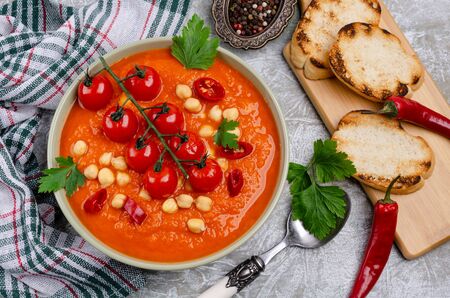 Red vegetable soup with chickpeas and parsley in a dish on a slate background. Selective focus.の写真素材