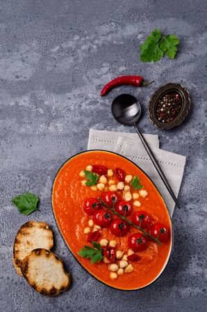 Red vegetable soup with chickpeas and parsley in a dish on a slate background. Selective focus.の写真素材