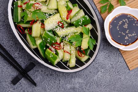Chinese cucumber salad with spices and sesame in a dish on a slate background. Selective focus.の写真素材