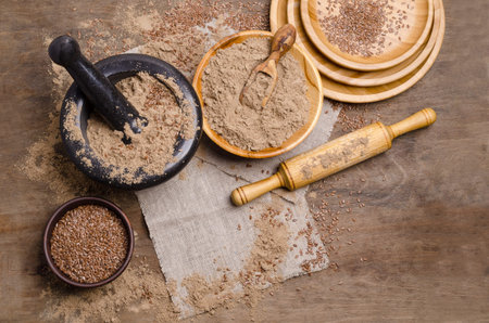 Flax flour with brown flax seeds on a rustic wooden background. Selective focus.の写真素材