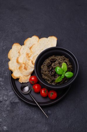 Traditional black tapenade with fried bread and tomatoes on slate background. Selective focus.の写真素材