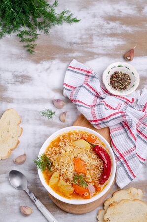 Thick vegetable soup with pasta in a ceramic bowl on a wooden background. Selective focus.の写真素材