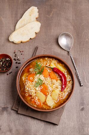 Thick vegetable soup with pasta in a ceramic bowl on a wooden background. Selective focus.の写真素材